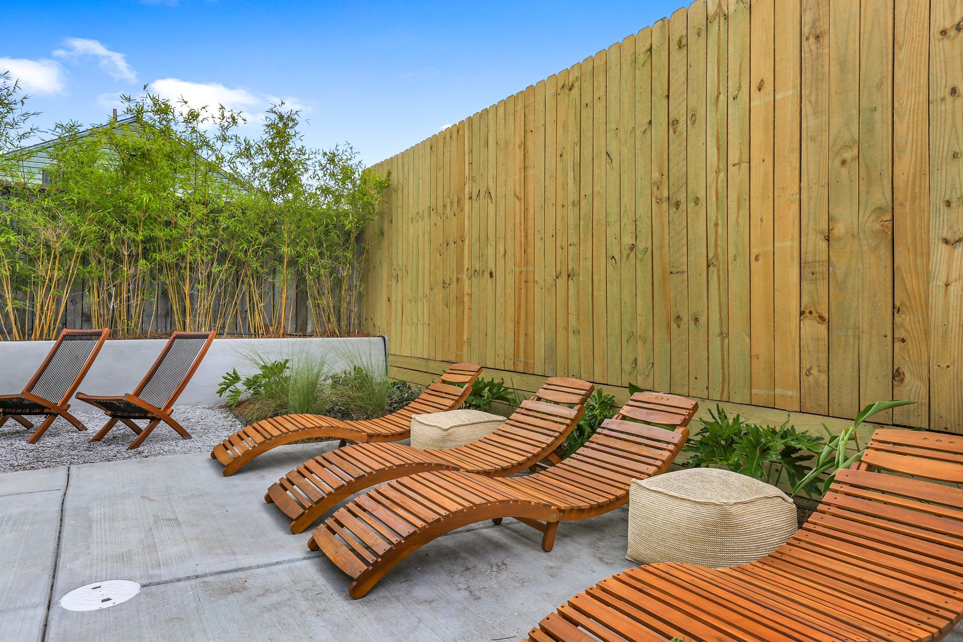 A row of wooden lounge chairs sitting next to a wooden fence.