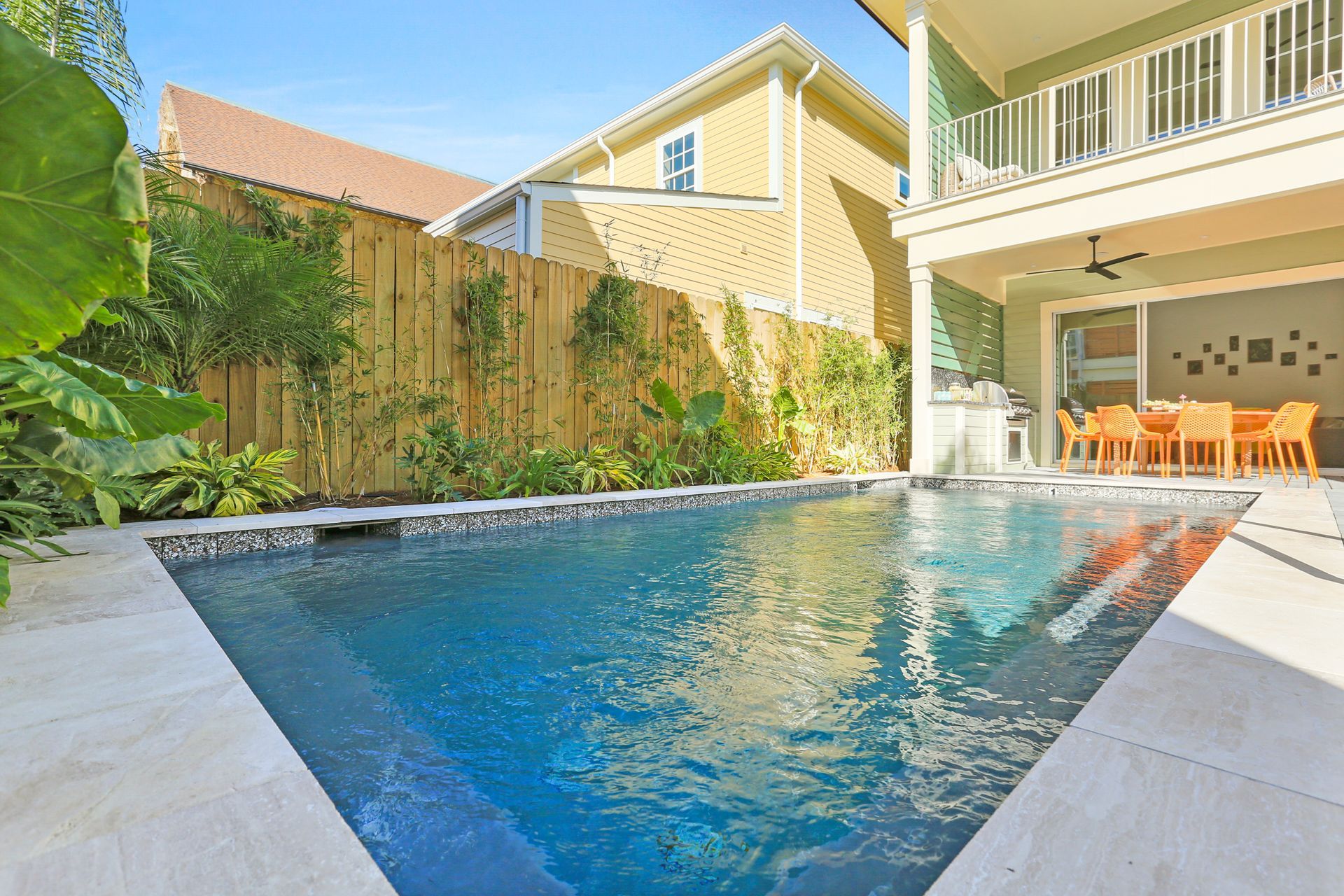 There is a large swimming pool in the backyard of a house.