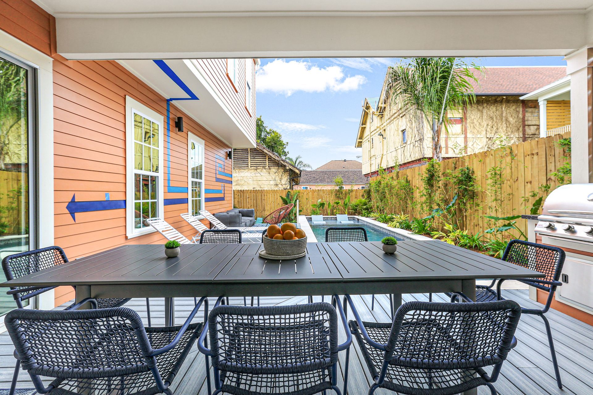 A patio with a table and chairs and a swimming pool in the background.