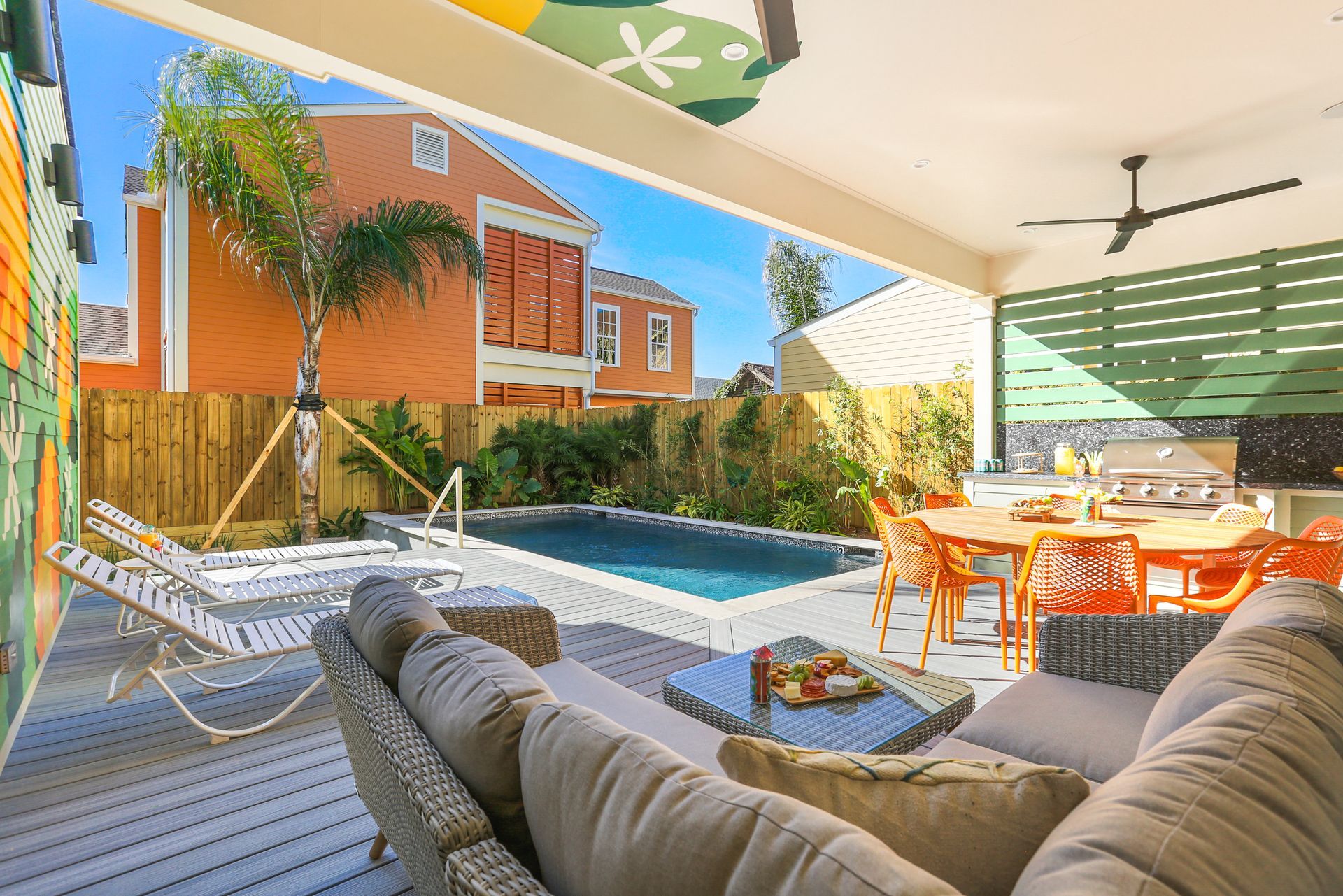A patio with a couch , table , chairs and a swimming pool