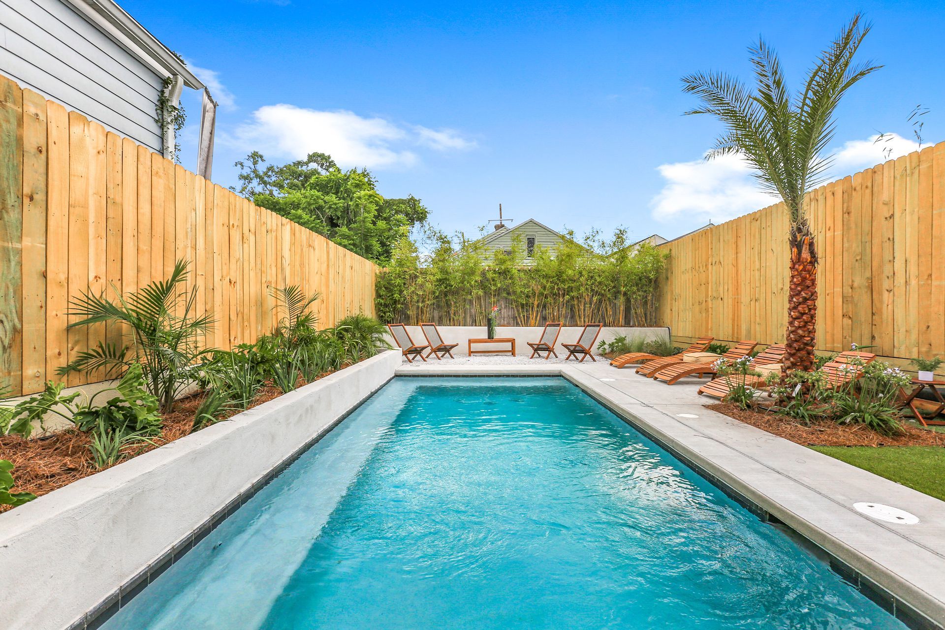 A swimming pool in the backyard of a house with a wooden fence surrounding it.
