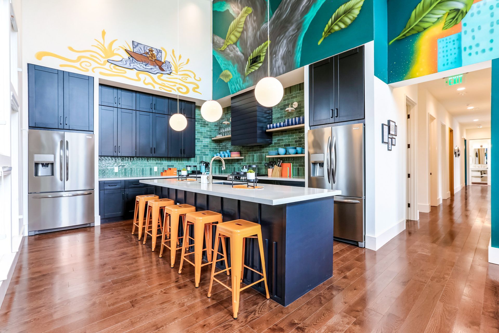 A kitchen with a large island and stools and a mural on the wall.