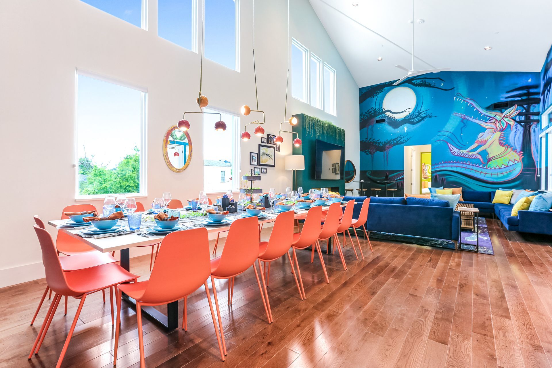 A large room with a dining table and chairs and a mural on the wall.