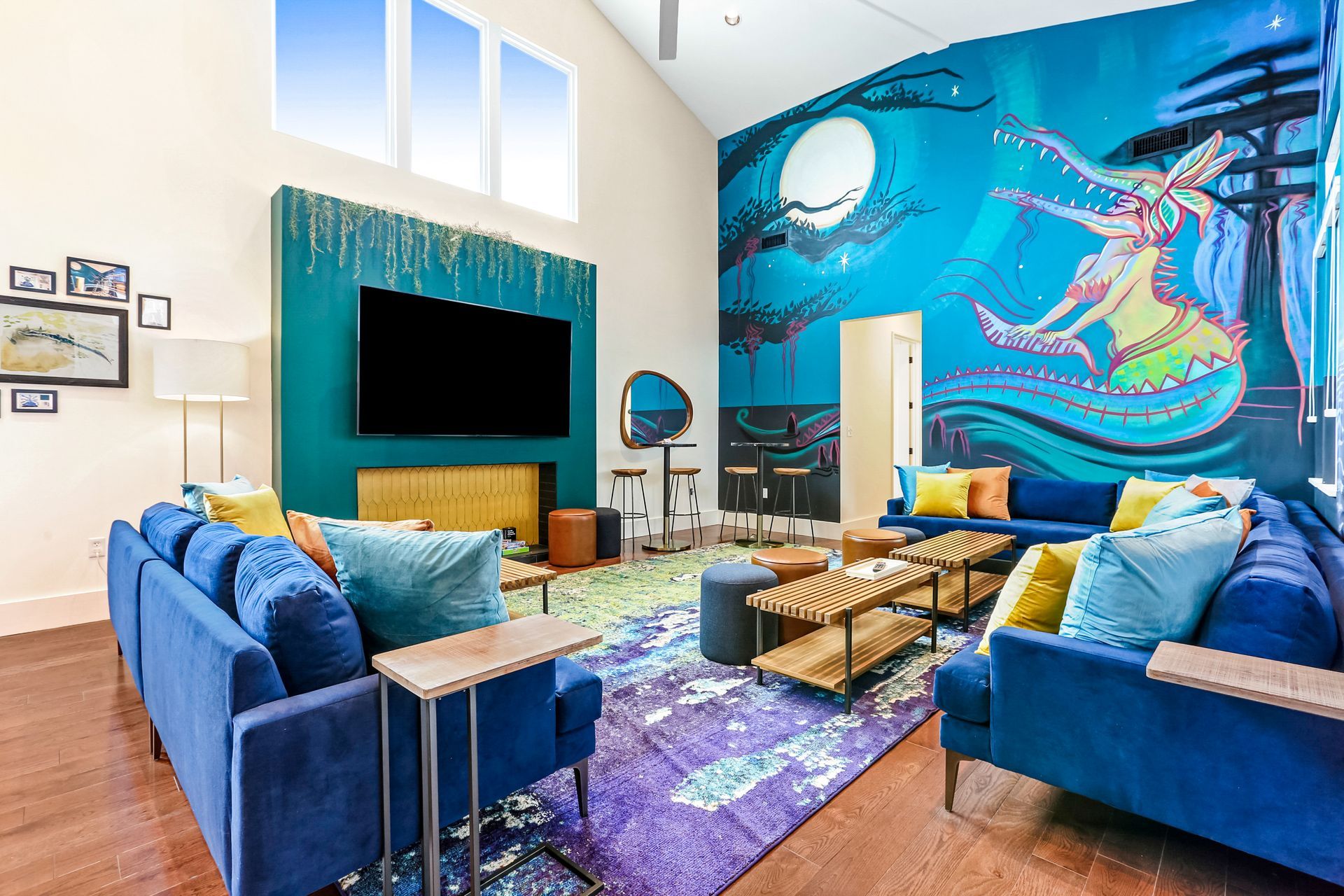A living room with blue furniture and a mural on the wall