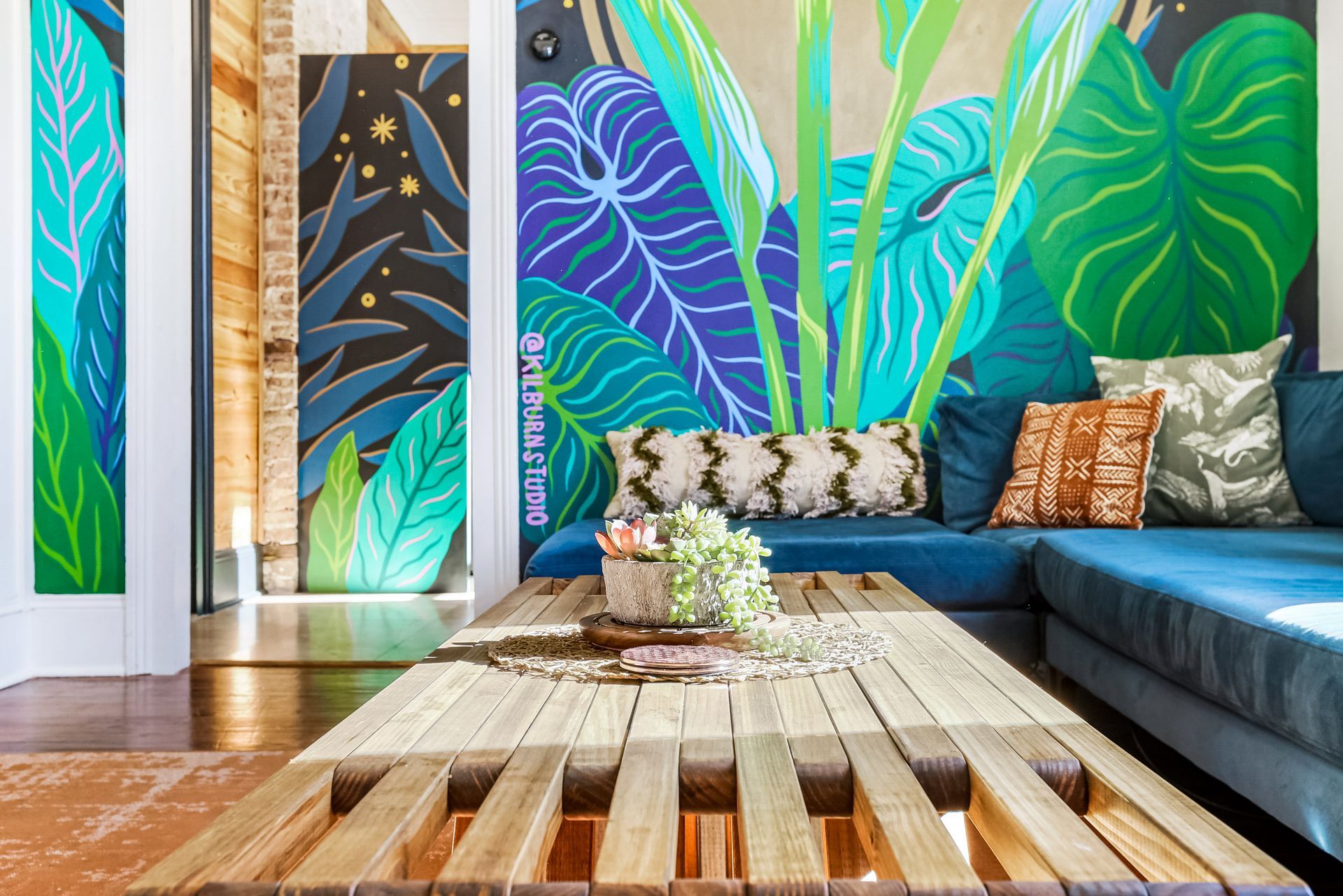 A living room with a blue couch and a wooden table.
