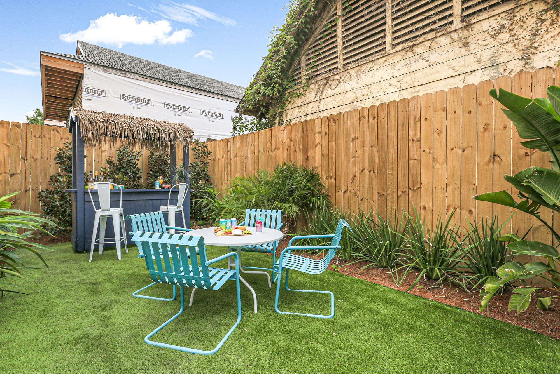 A backyard with a table and chairs and a wooden fence.