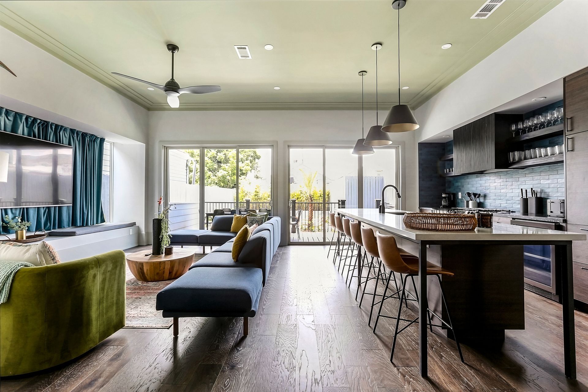 A living room with a couch , chairs , a table and a kitchen.