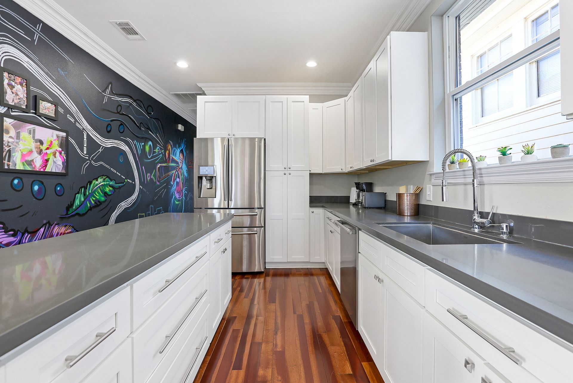 A kitchen with white cabinets , stainless steel appliances , a sink , and a chalkboard wall.