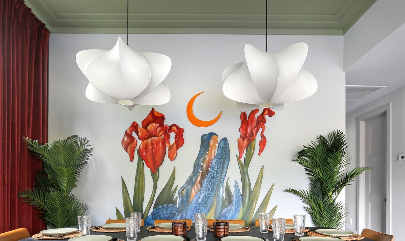 A dining room with a table and chairs and a mural on the wall.