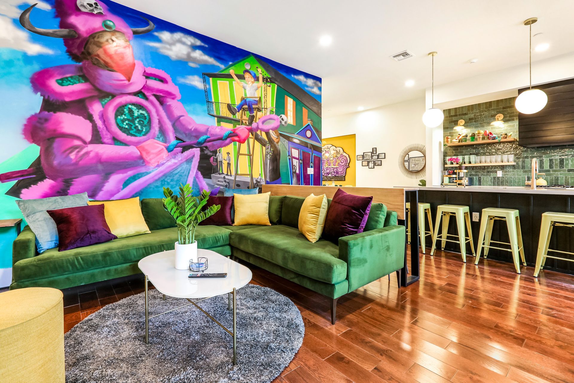 A living room with green couches and a mural on the wall.