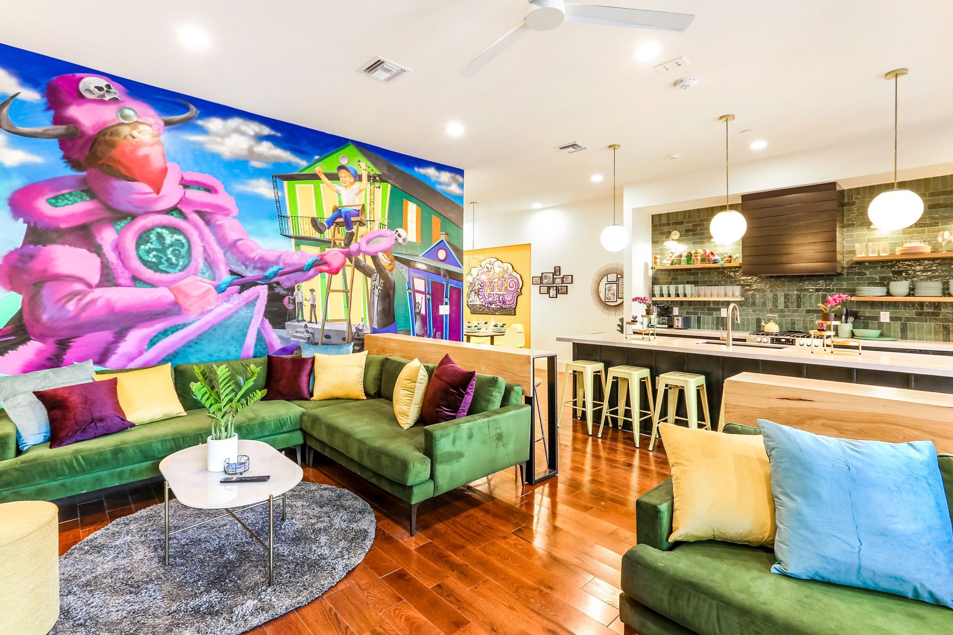 A living room with green couches and a mural on the wall.