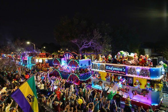 a large crowd of people are watching a parade at night .