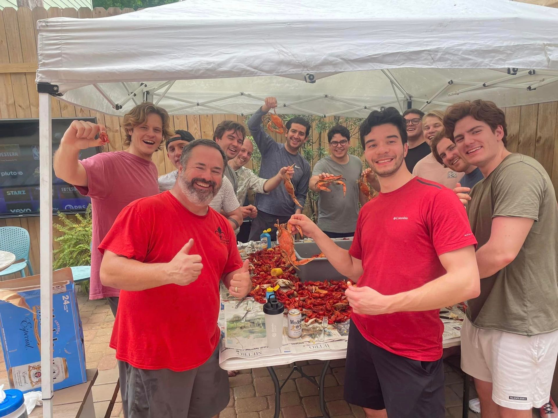 a group of young men are standing under a tent eating crawfish .