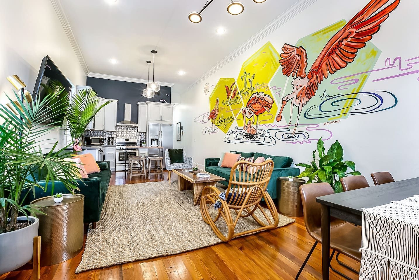 A living room with colorful furniture and a mural on the wall.