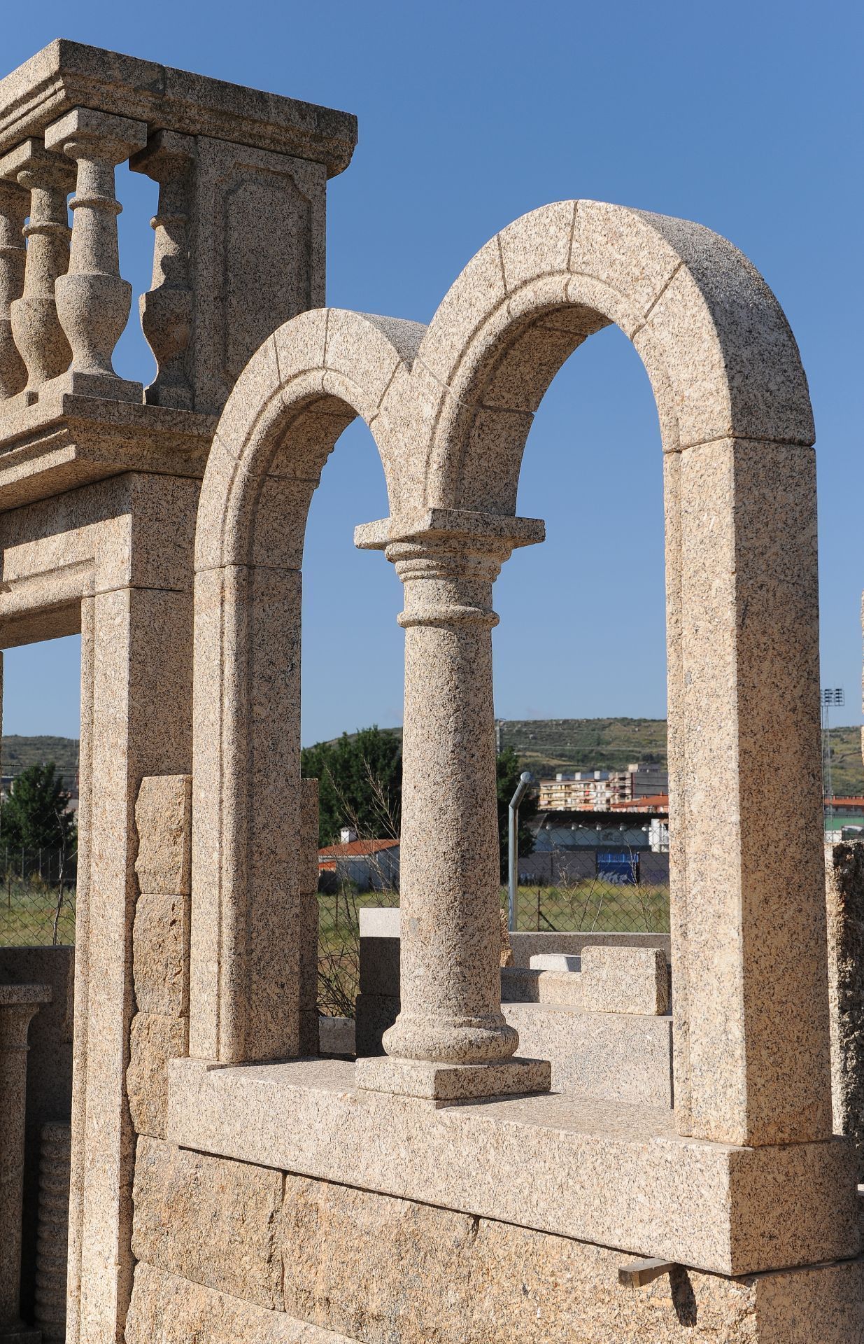 Estructura de granito color beige con doble arco, pilar central y balaustrada, que se alza contra un cielo azul despejado.