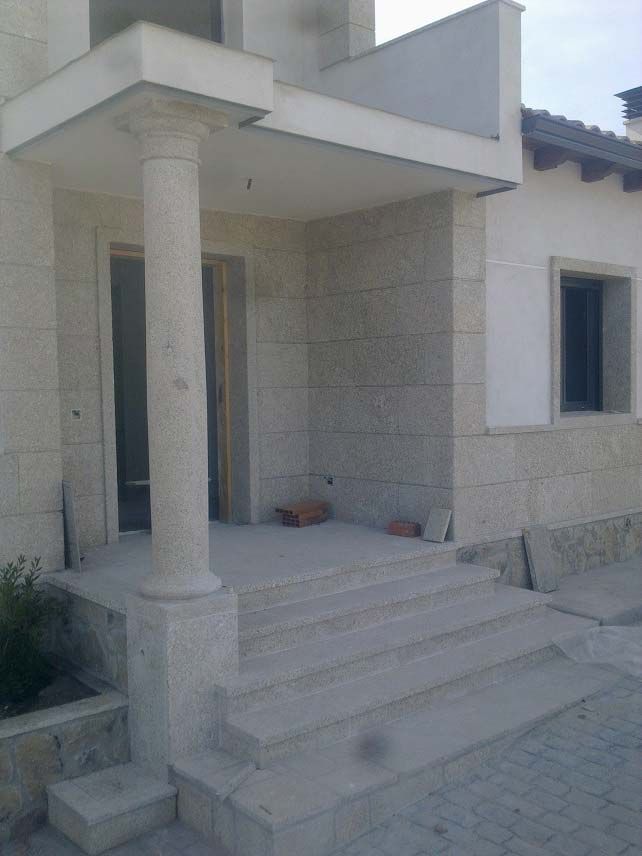 Una entrada de piedra con un pórtico sostenido por columnas y amplios escalones que conducen a la puerta principal.