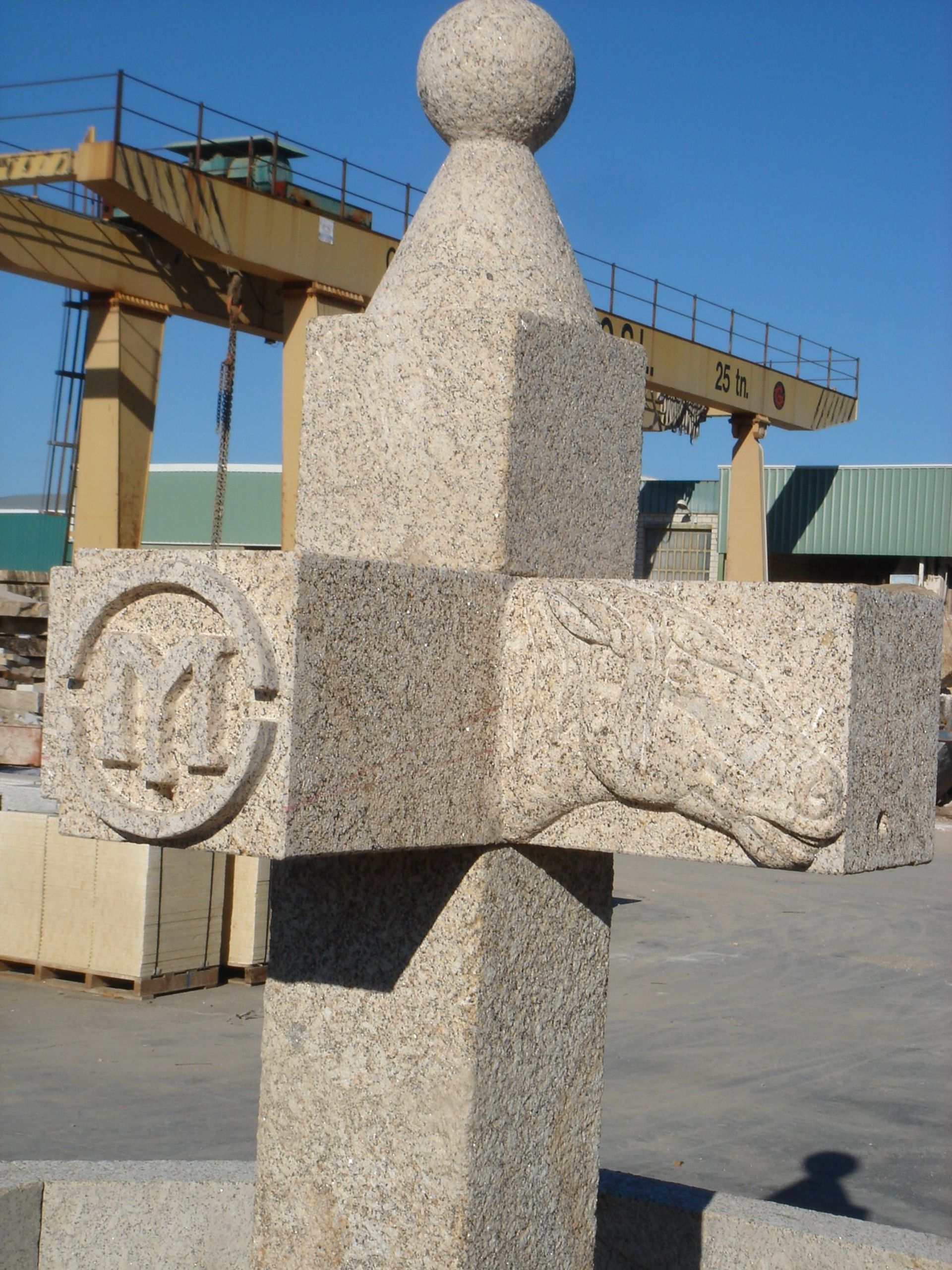 Una cruz de piedra con una esfera en la parte superior y una