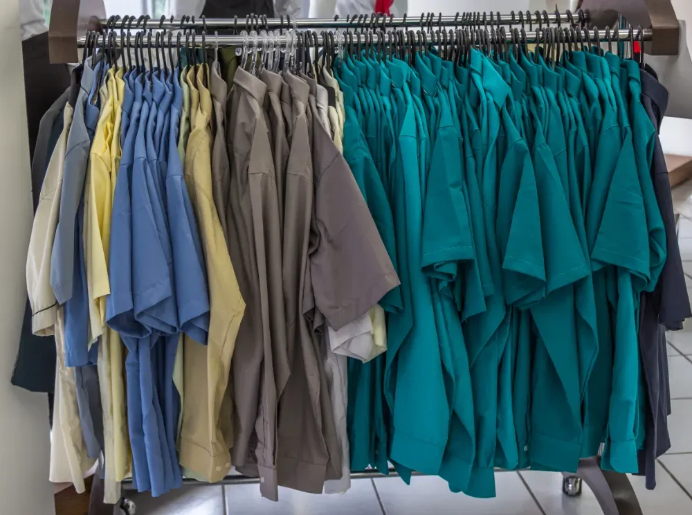 Primer plano de camisas con cuello en varios colores y rayas colgadas en perchas negras.