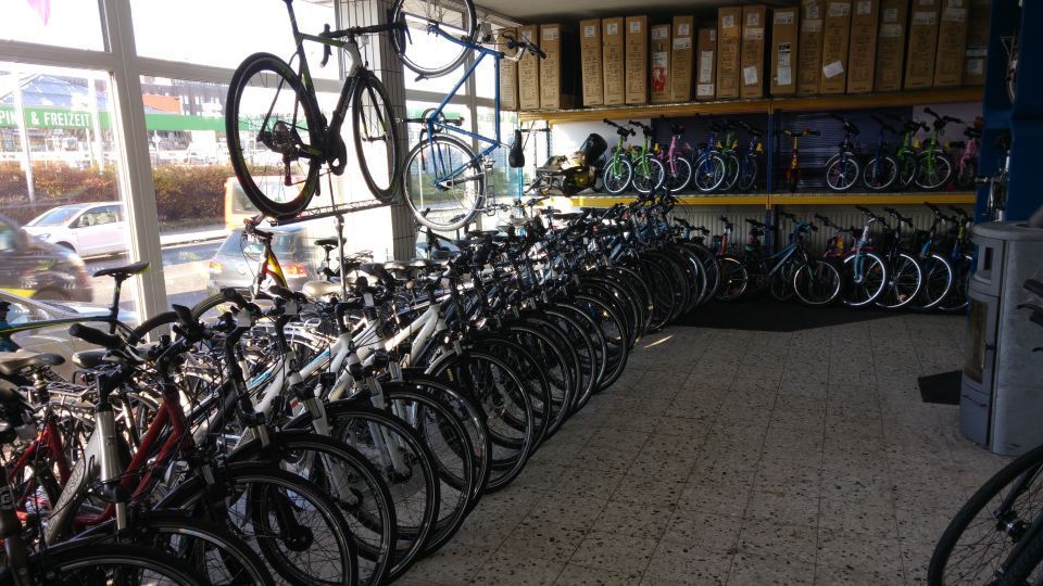 Fahrräder stehen in einem Fahrradladen. Einige hängen an der Wand, andere stehen auf dem Boden. Innenaufnahme.