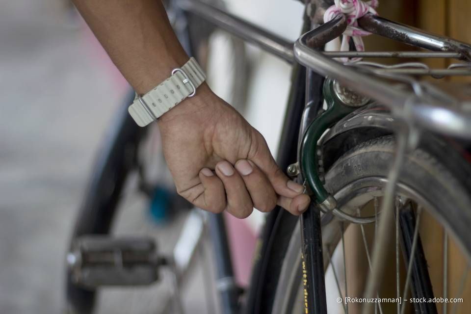 Eine Hand justiert die Bremse eines Fahrrads. Das Fahrrad ist schwarz-grün, und die Person trägt eine weiße Uhr.