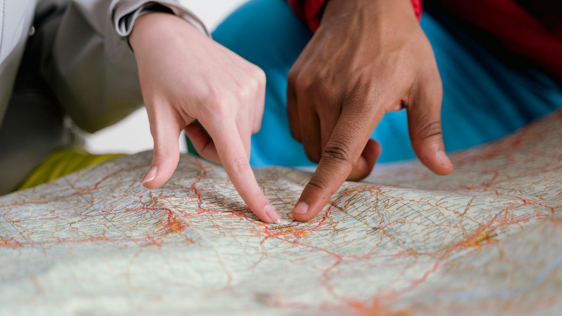 Un mapa, con dos manos señalando con los dedos a un punto del mapa 