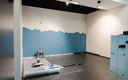 Chambre en rénovation avec mur peint en bleu, sol gris et outils.