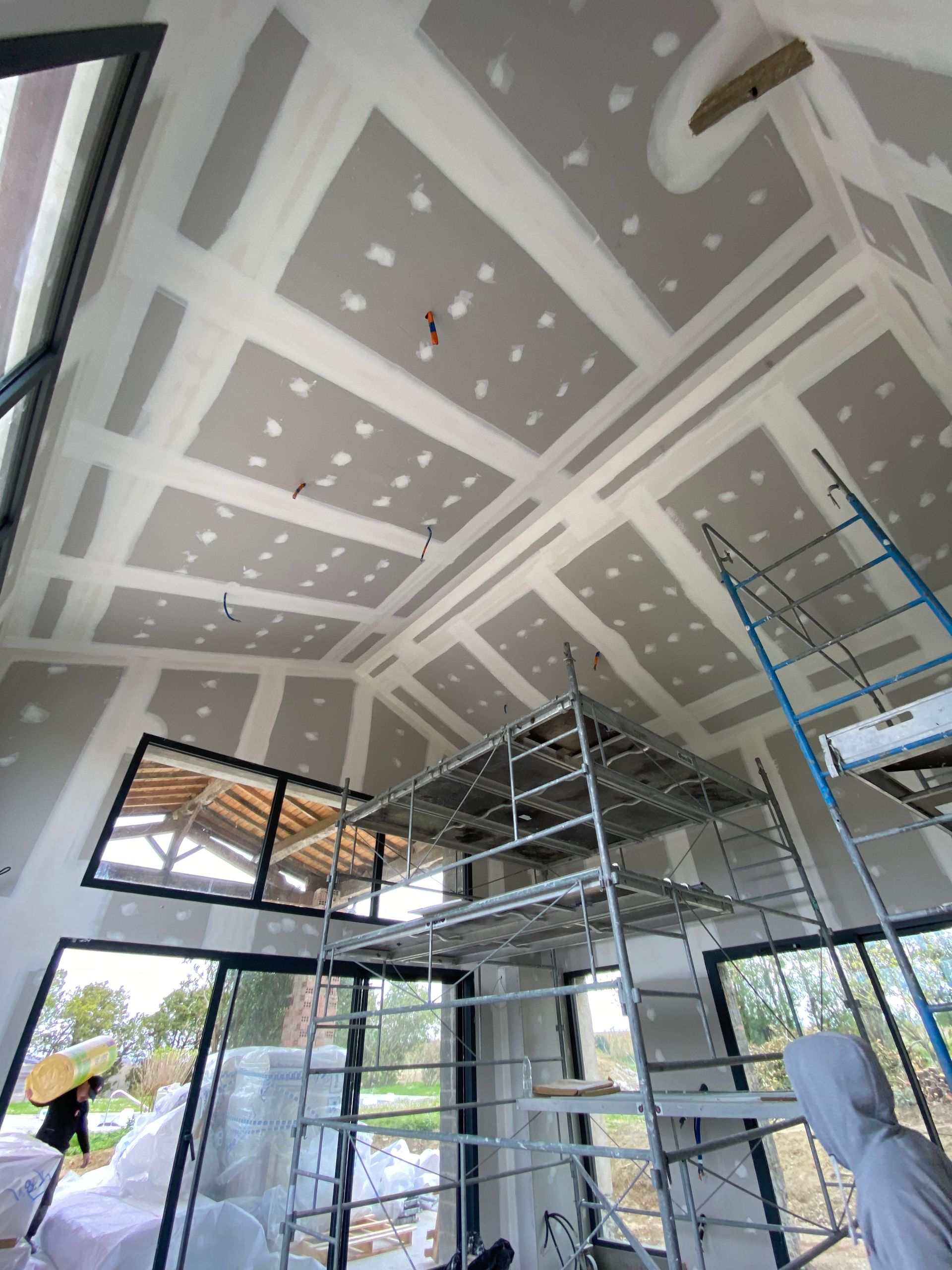 Plafond et murs en cloisons sèches avec composé à joints et fils partiellement terminés.