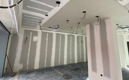 Pièce intérieure avec cloisons sèches partiellement installées, montrant des montants exposés et des murs non finis.