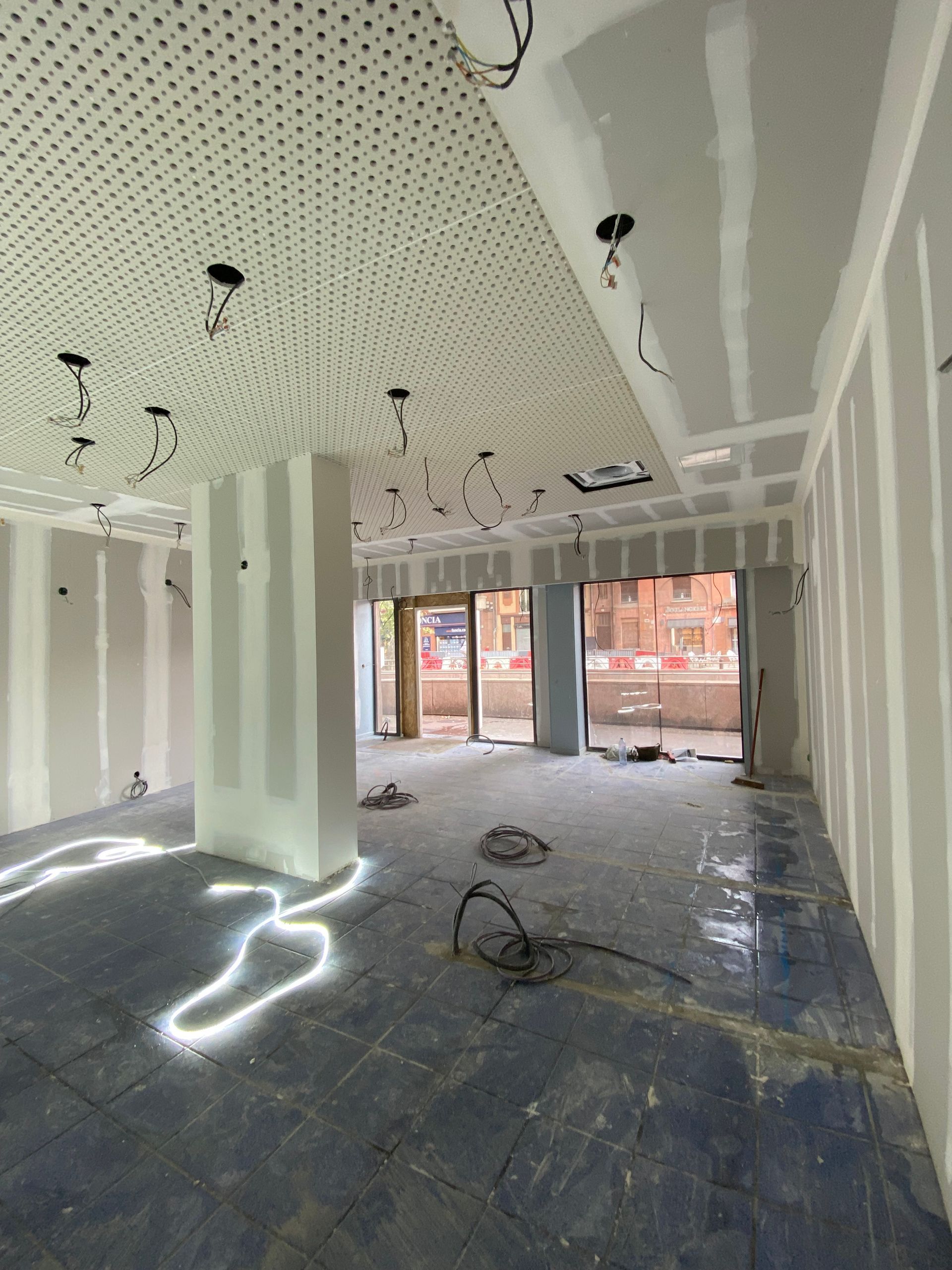 Pièce en construction avec cloisons sèches et montants apparents ; un plancher et un plafond en béton sont visibles.