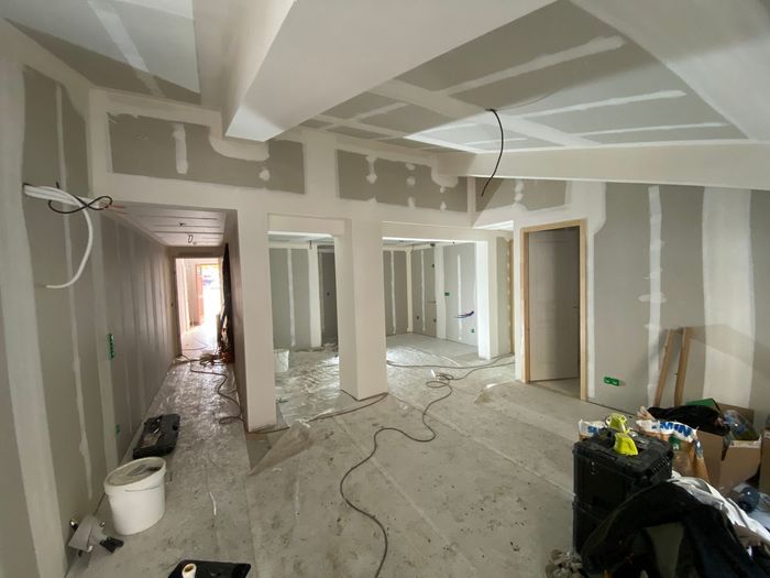 Intérieur avec cloisons sèches non finies, peinture blanche et sol en béton.