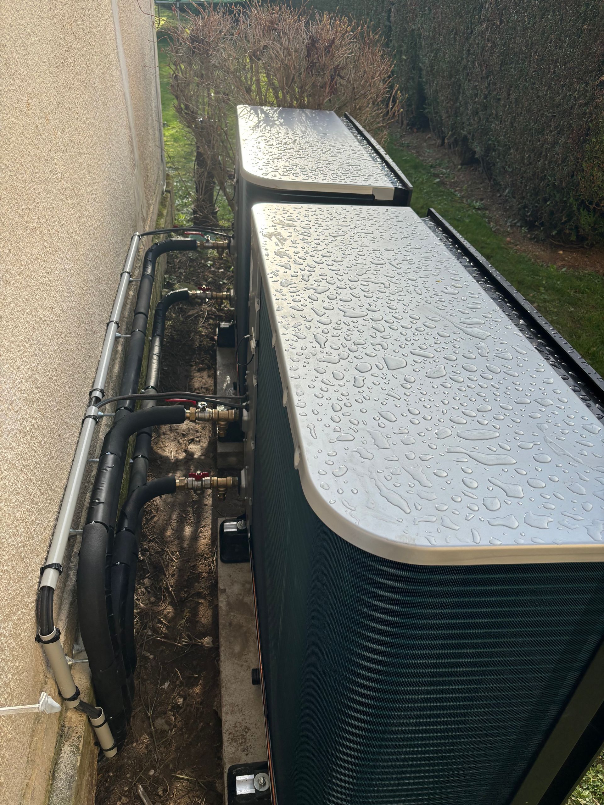 Pompe à chaleur à l'extérieur d'une maison couverte de gouttes de pluie
