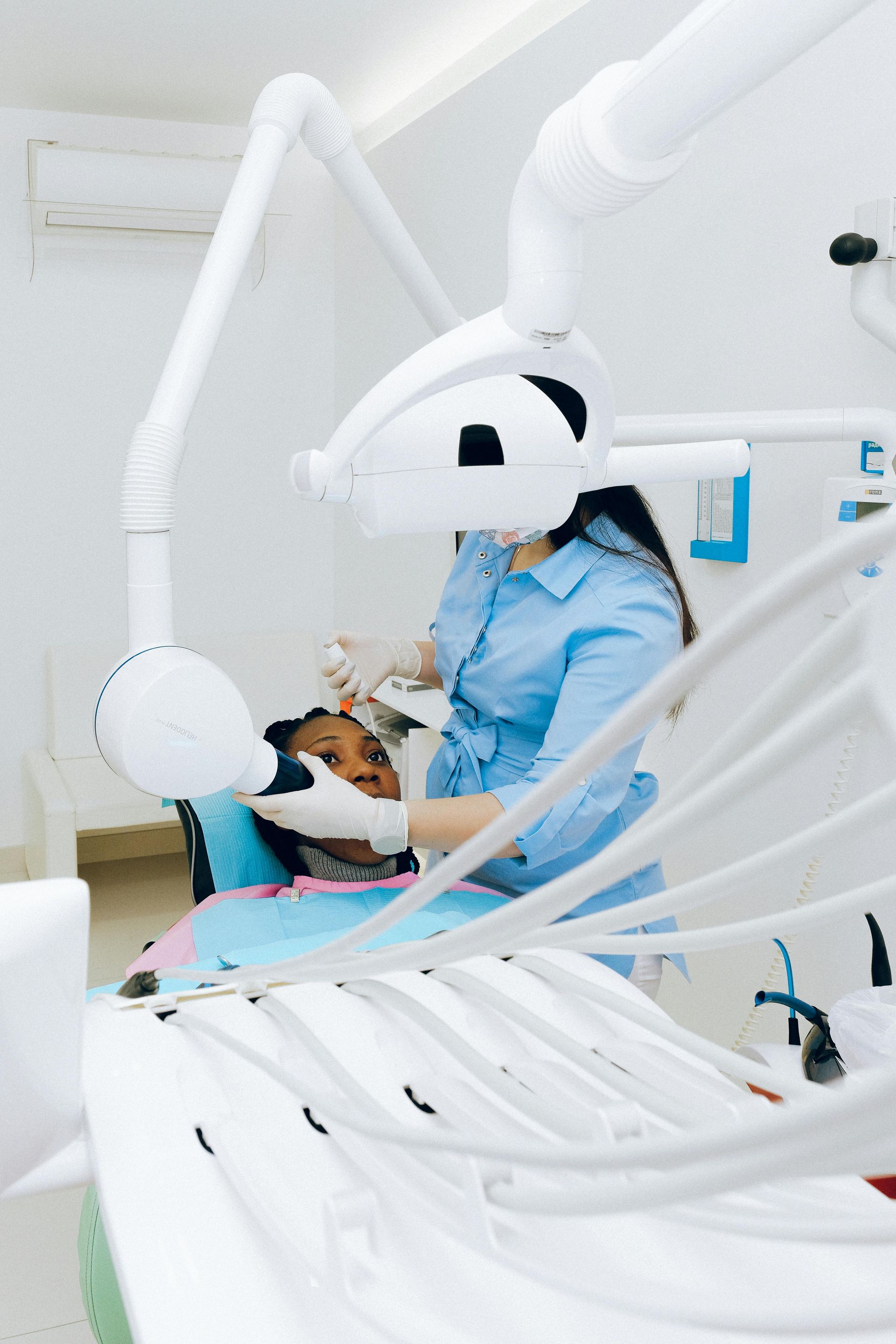 Dentista examinando a boca de um paciente em um consultório odontológico moderno e bem iluminado.