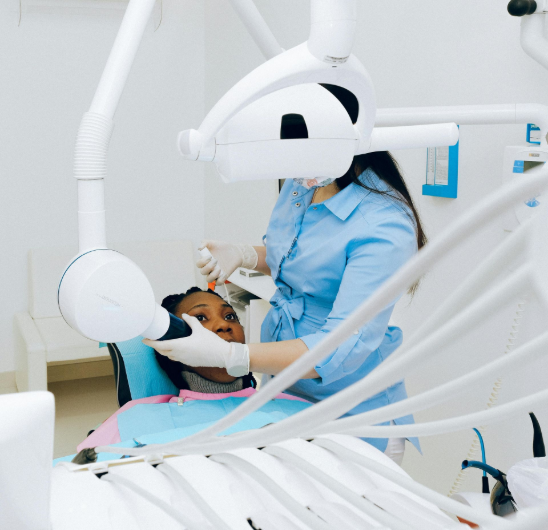 Dentista examinando a boca de um paciente em um consultório odontológico moderno e bem iluminado.