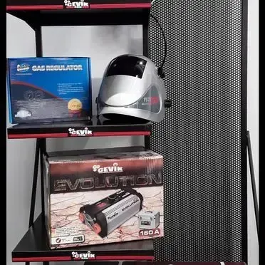 Un casco de soldar está colocado encima de un estante al lado de una caja.