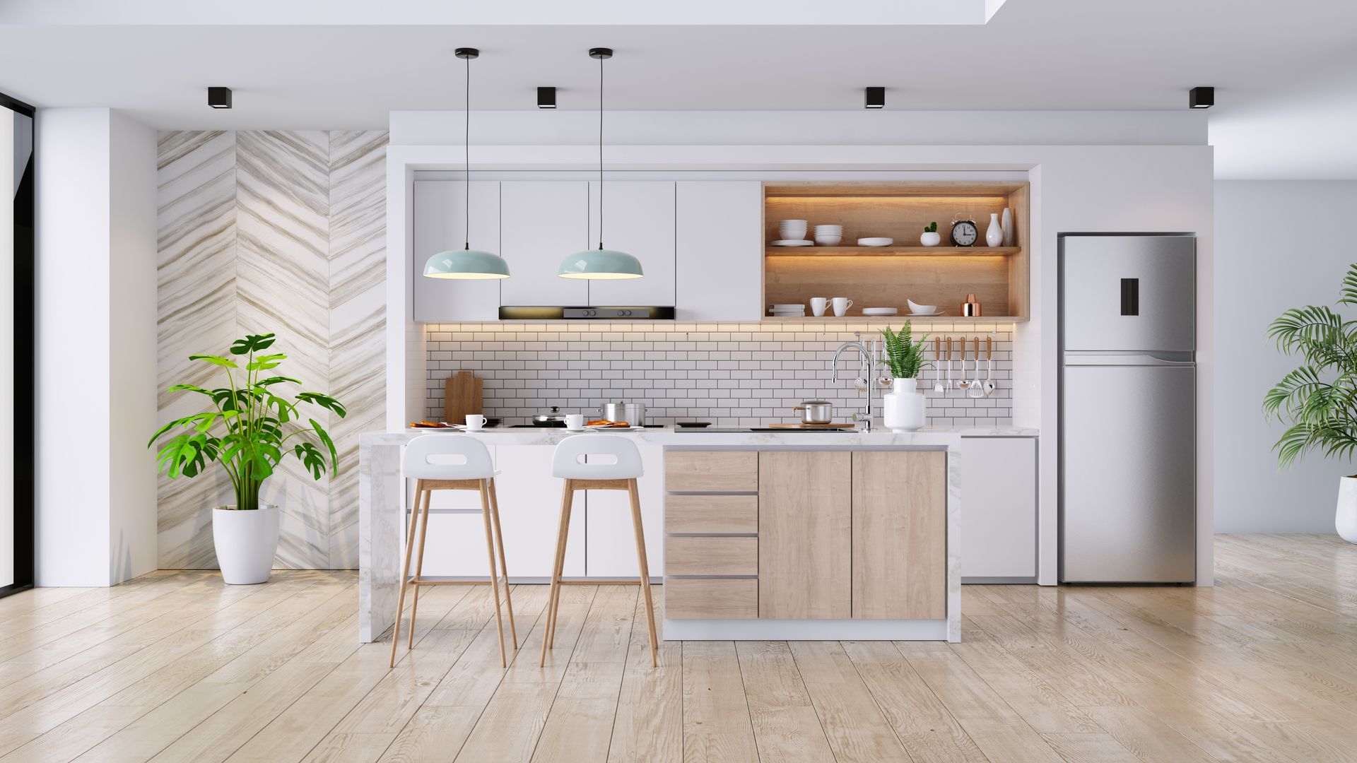 Cuisine blanche moderne avec îlot central, suspensions lumineuses, éléments en bois, plante en pot et réfrigérateur.