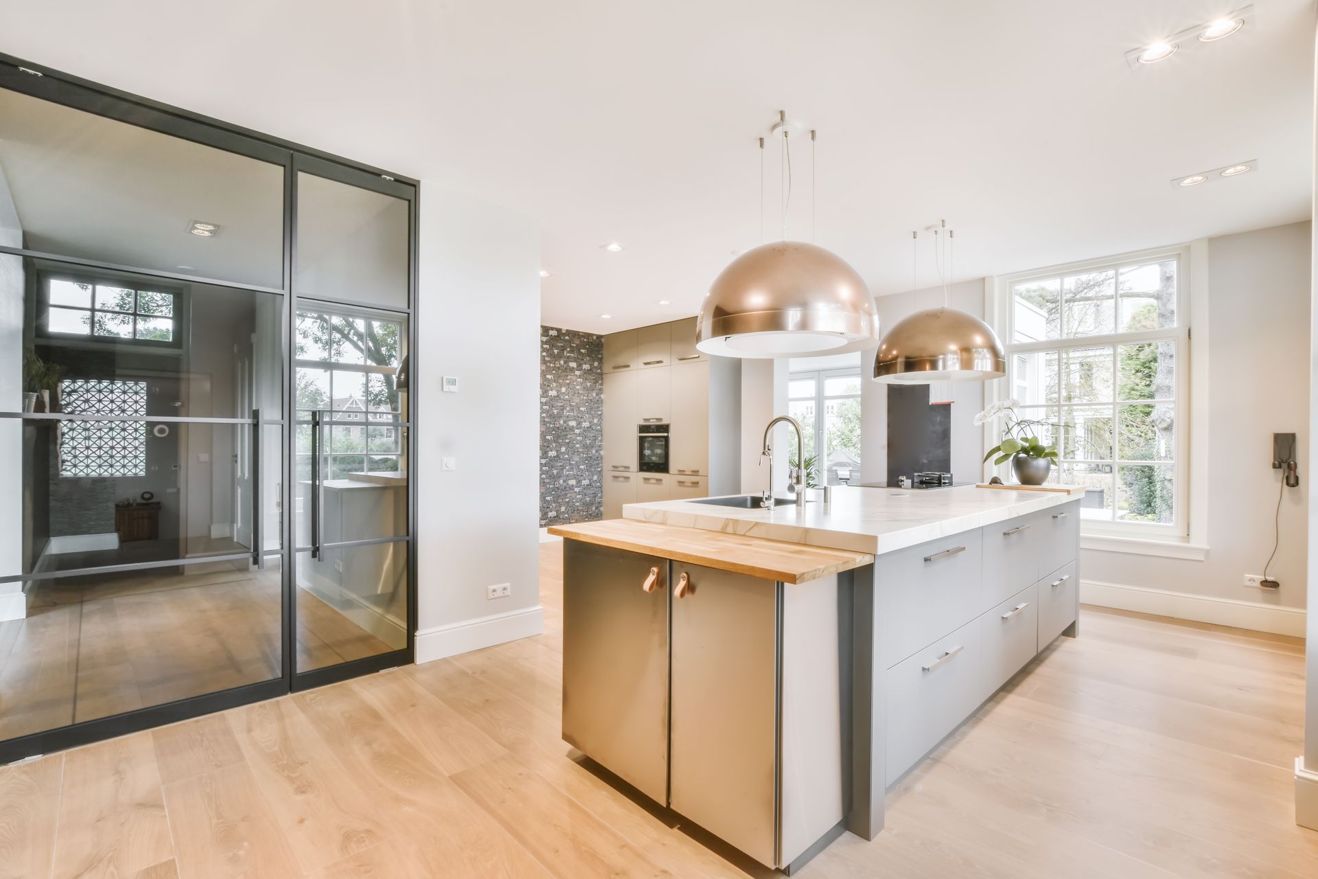 Cuisine moderne et lumineuse avec armoires blanches, îlot en bois et grandes portes vitrées