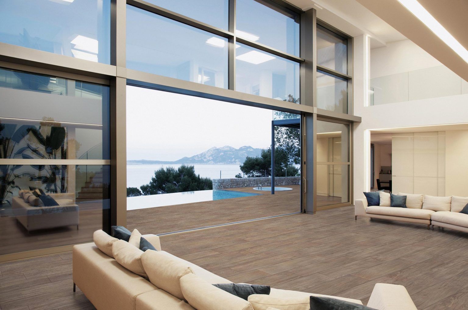 Salon moderne avec baies vitrées offrant une vue imprenable sur l'océan au coucher du soleil