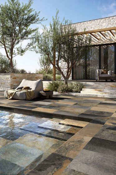 Patio avec dallage en pierre de Bali, chaise longue et piscine.