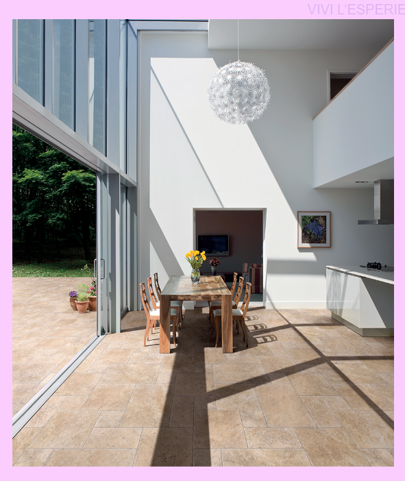 Salle à manger moderne et lumineuse avec de hautes fenêtres, une table en bois et une suspension lumineuse donnant sur un jardin.