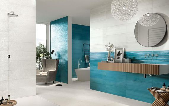 Salle de bains moderne avec carrelage turquoise, meuble lavabo en bois, miroir rond et murs blancs.