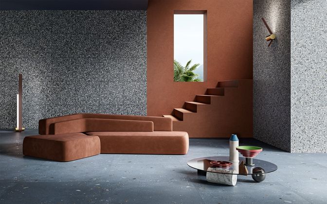 Salon avec canapé d'angle marron, murs mouchetés, escalier et table basse.