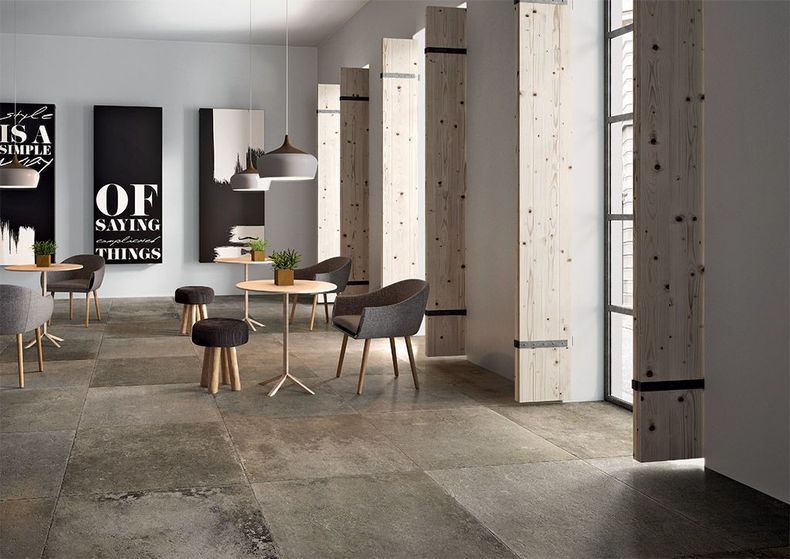 Hall d'entrée avec colonnes en béton, fauteuils et petite table près de grandes fenêtres