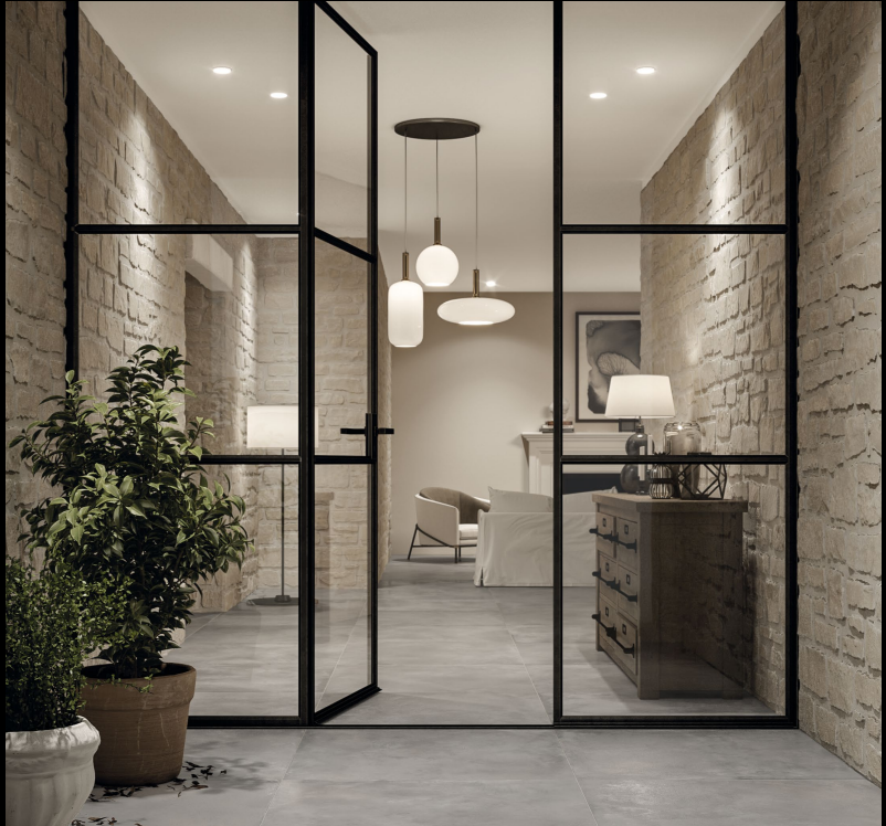 Hall d'entrée moderne avec portes vitrées, murs en pierre et luminaires suspendus.