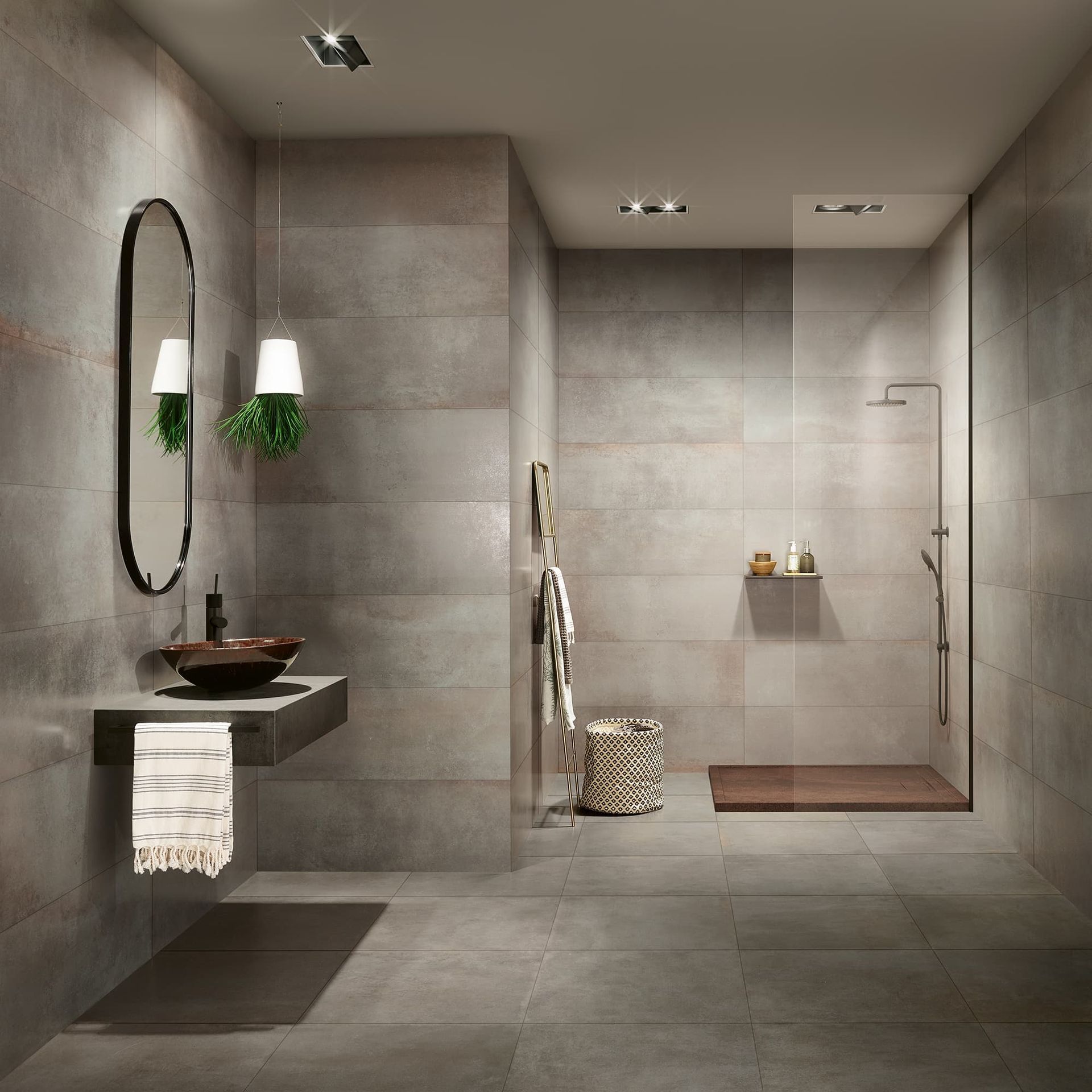 Salle de bains moderne carrelée de gris avec douche à l'italienne, miroir mural, lavabo suspendu et luminaires suspendus.