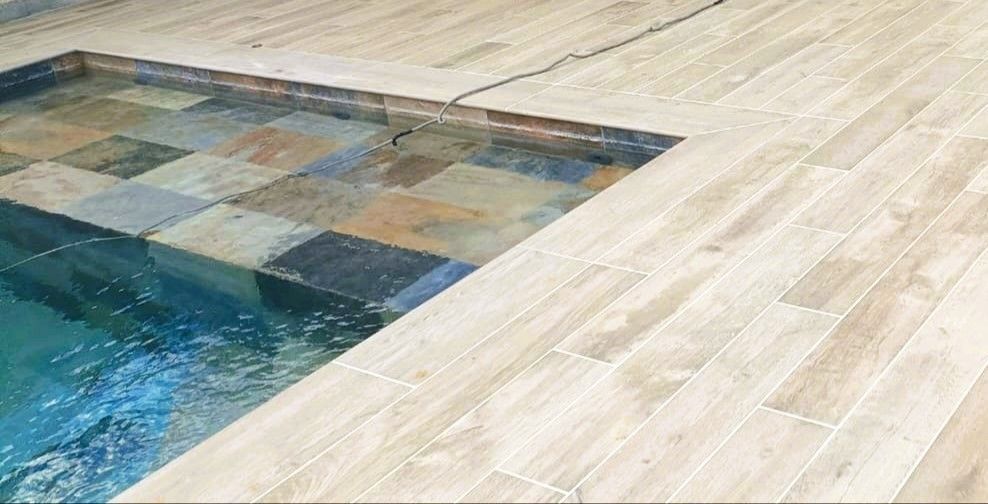 Bordure de piscine avec un carrelage effet pierre de Bali.