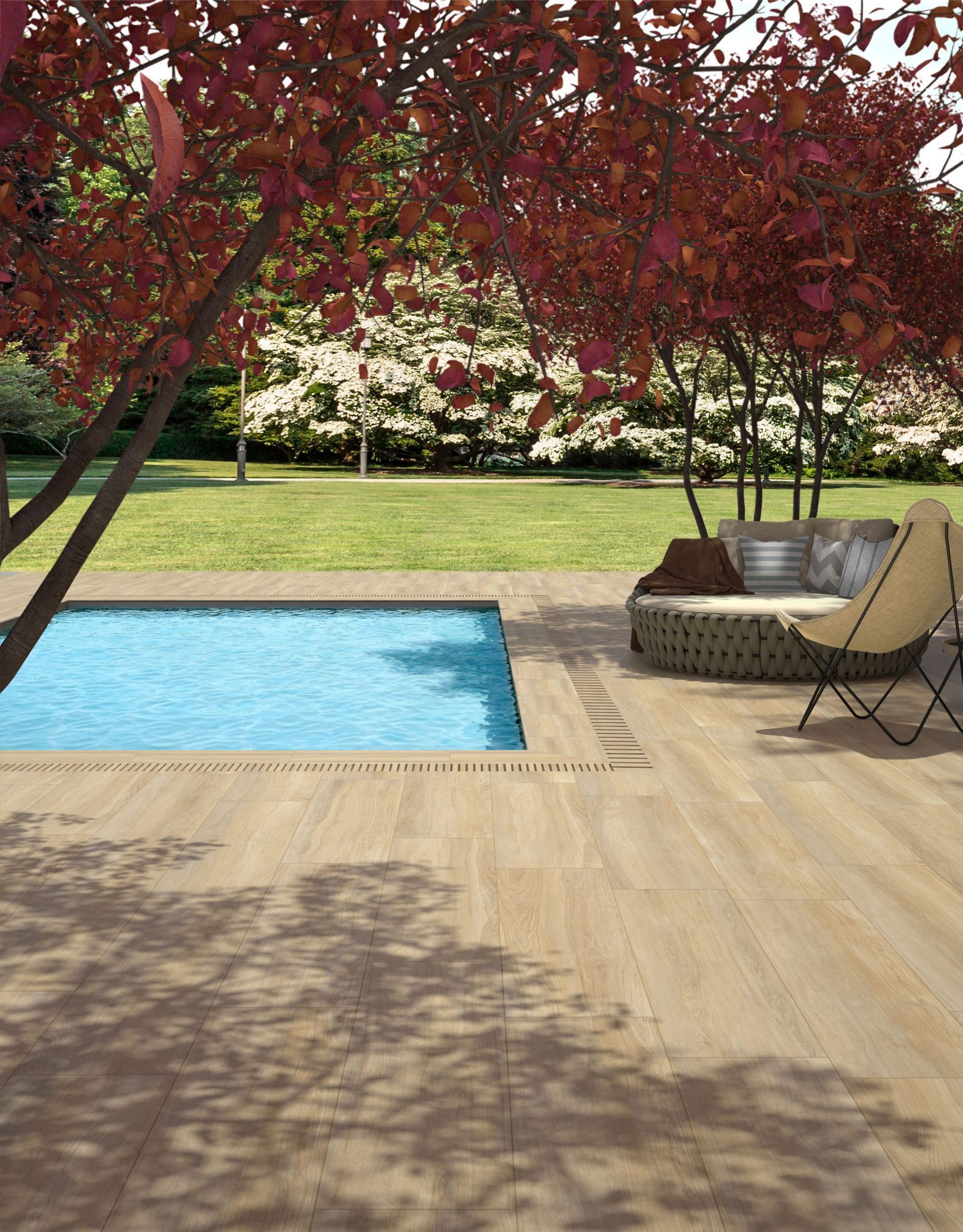 Piscine avec terrasse en bois, arbres à feuilles rouges et coin salon de jardin ensoleillé