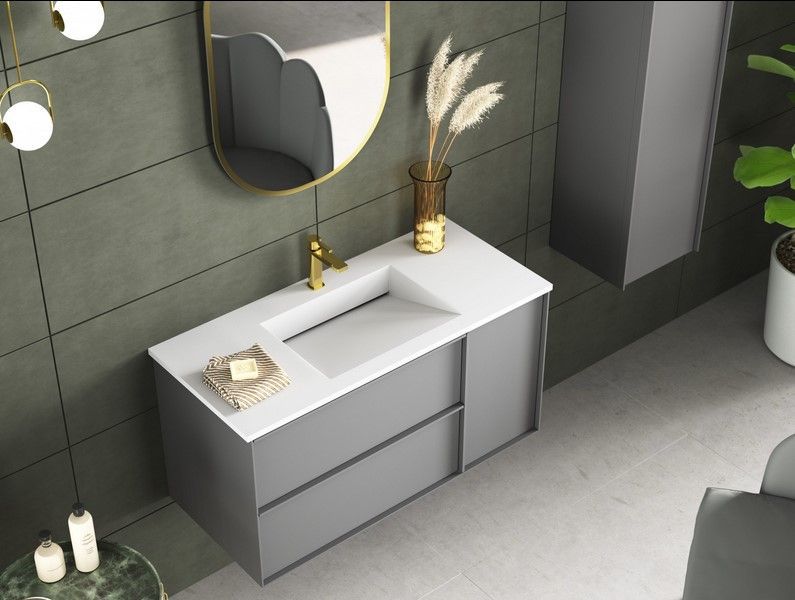 Meuble lavabo gris moderne avec lavabo blanc, robinet doré, miroir et éléments décoratifs.