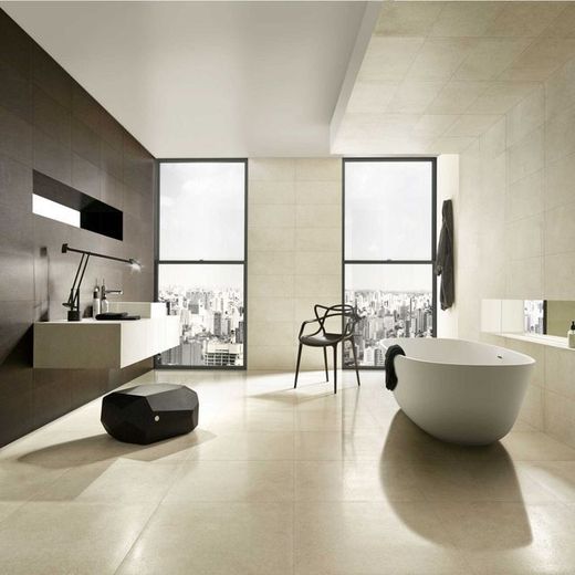 Salle de bains avec baignoire îlot, lavabo suspendu et grandes fenêtres offrant une vue sur la ville