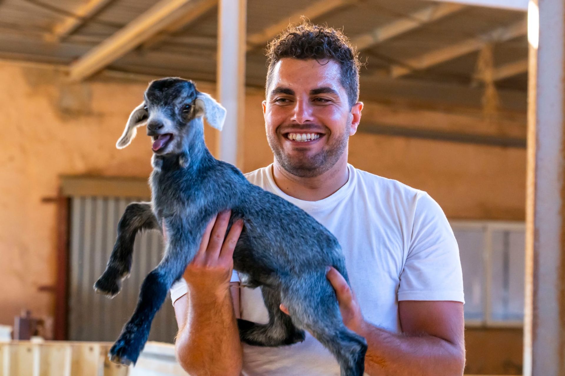 Un hombre sostiene un cabrito en sus brazos.