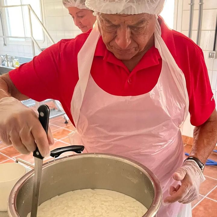 Un hombre con una camisa roja y un delantal blanco está revolviendo una olla de comida.